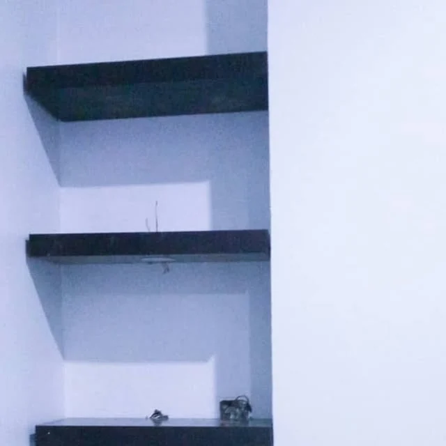 Dark floating shelves fitted into a wall niche